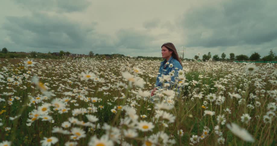 A woman is standing quietly in a field of flowers
