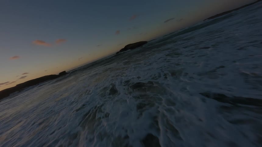 Large rocks are on a beach in a coastal area getting washed by waves