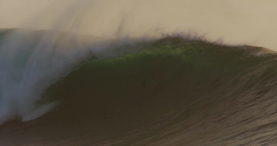 The barrel of a large wave partially collapses as the wave rolls