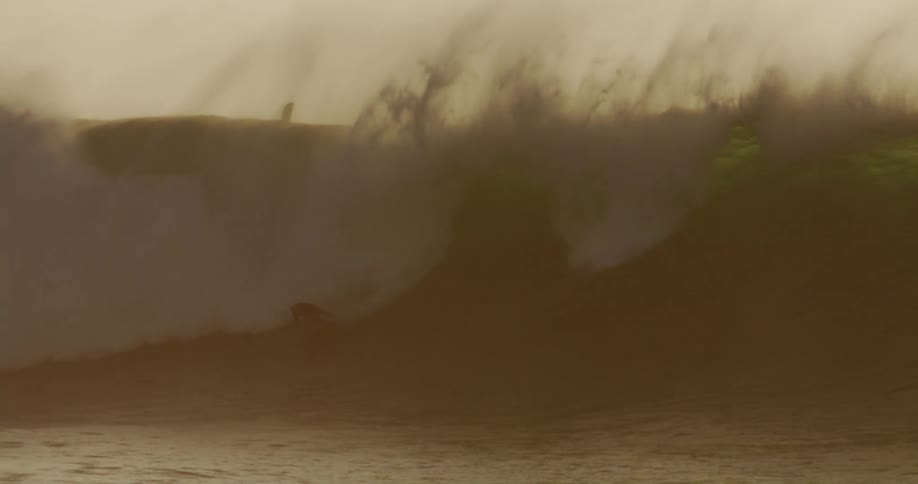 A person surfing in the ocean as powerful waves crash around them under the bright midday sun