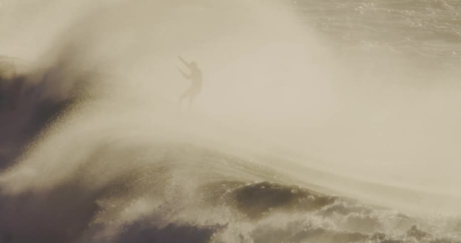 A surfer makes it over the top of a wave just as the barrel starts to collapse
