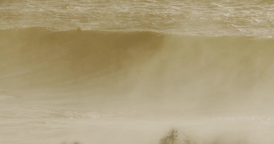 Men wait on their surfboards as a wave rolls under them