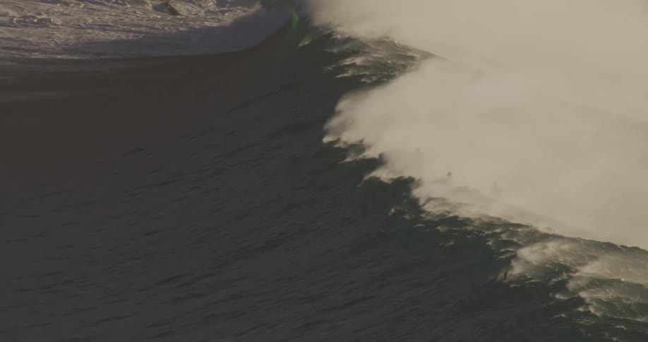 A group of people sitting patiently on their surfboards in the ocean waiting to catch the forming waves under the midday sun