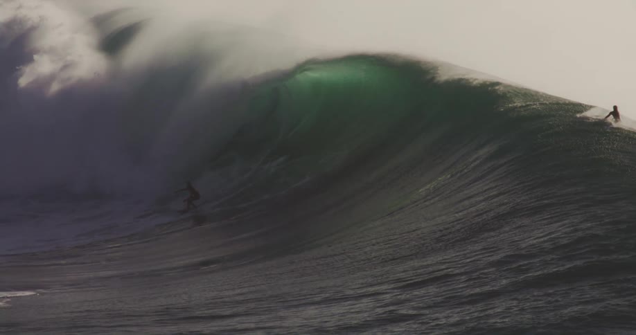 The surfers are riding a long wave