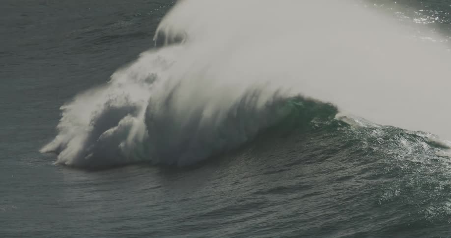 Heavy waves form in the ocean creating foamy substances as the water splashes at midday