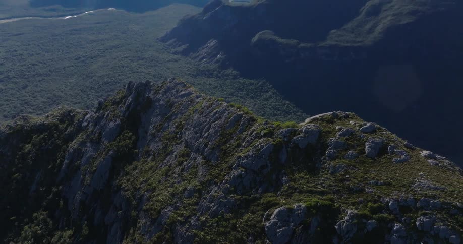 A mountain peak covered in green vegetation and grasses at midday