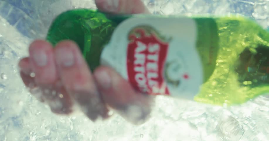 Hand picking up a bottle of beer from ice water