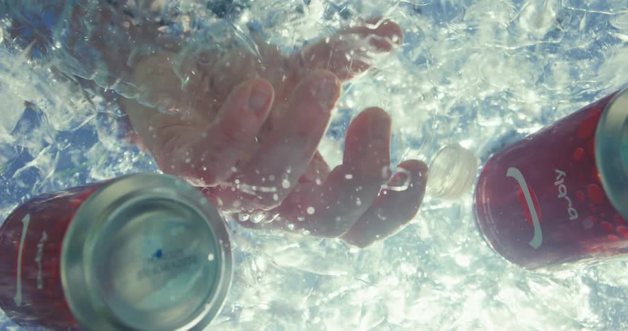 Hand reaches into the icy water to grasp a water bottle