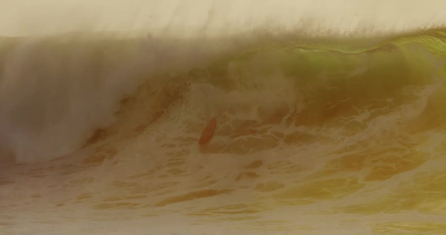 Surfer riding a large breaking wave falls off his surfboard