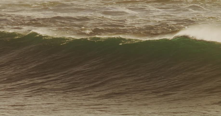 Aerial view of an ocean wave crashing in slow motion