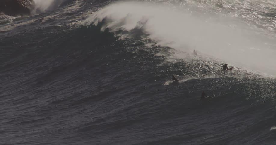 A wave passes by the swimming surfers