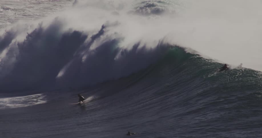 A surfer rides the wave past other surfers