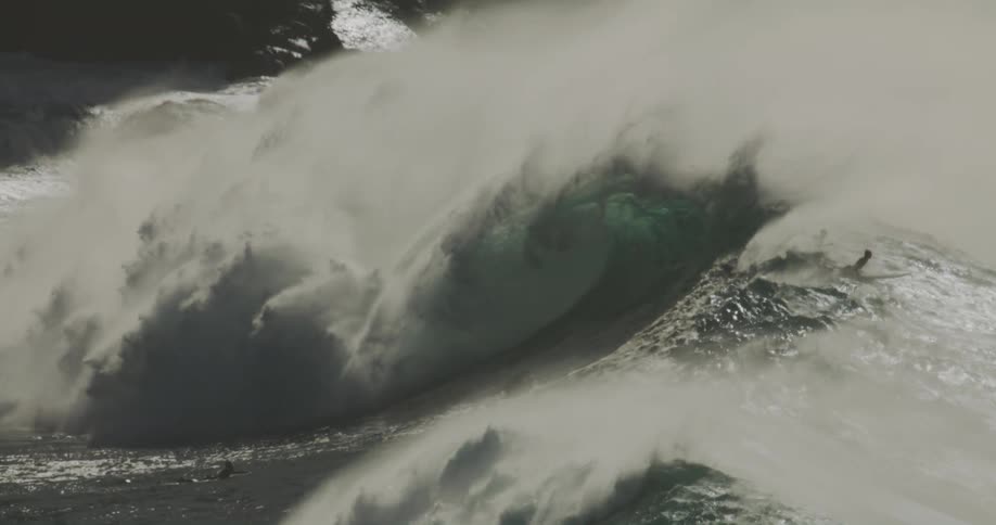 Surfers lie on their surfboards as the breaking wave passes under them