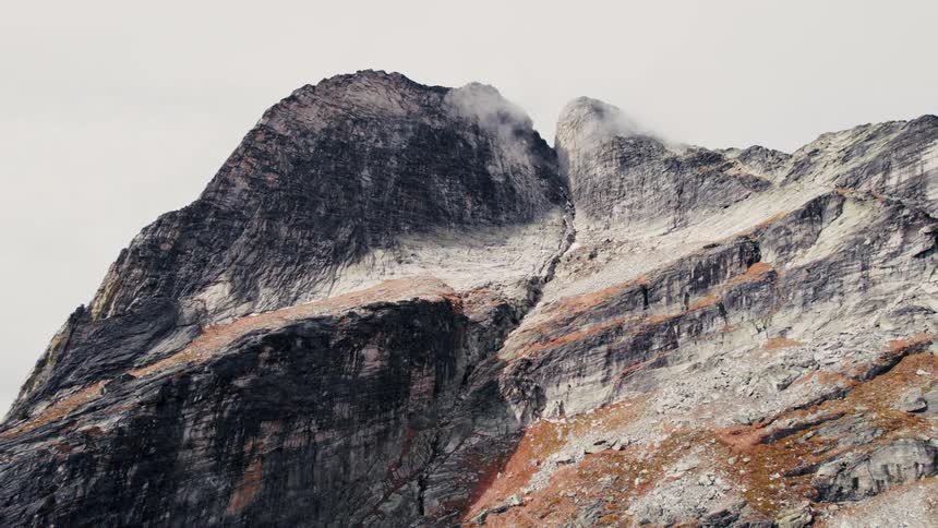 The cloud touches the peak of the tall mountain