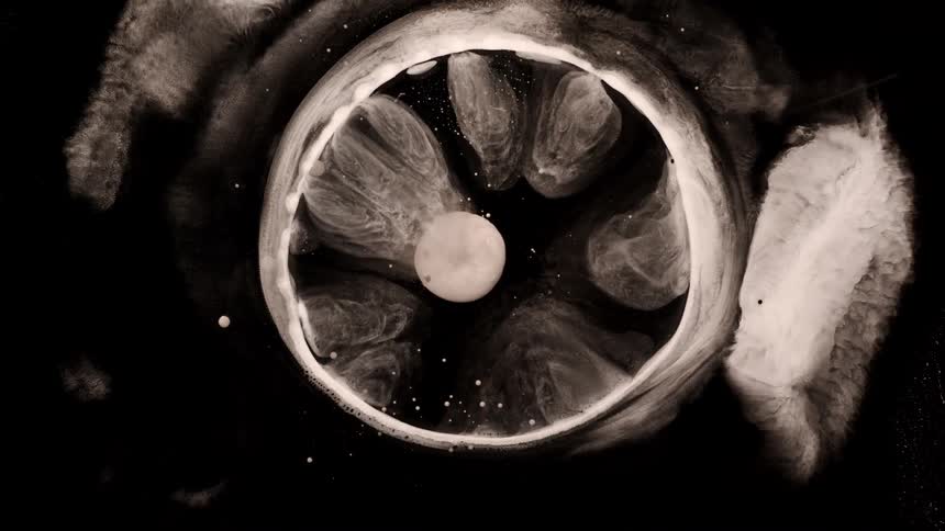 Abstract liquid matter expanding against a dark background