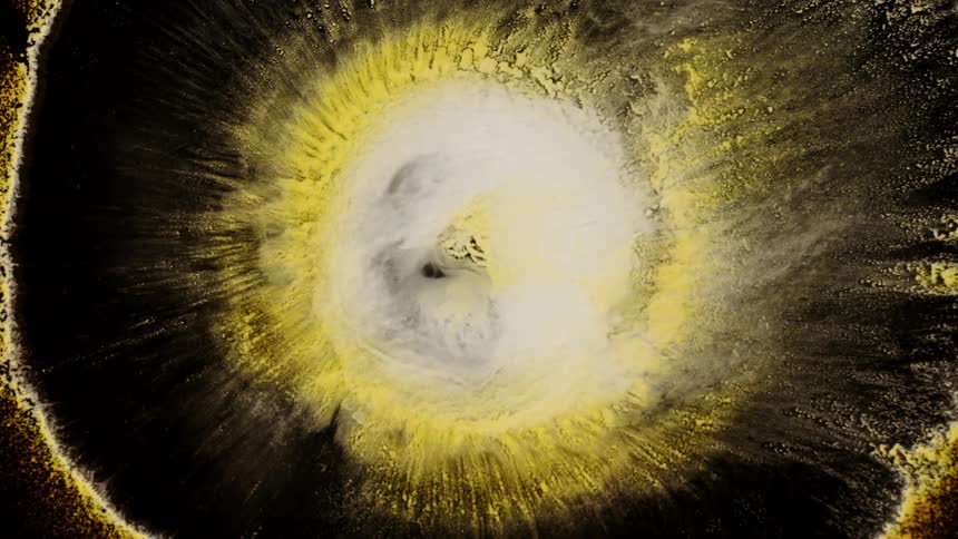 A large gold rock explodes in the galaxy as tiny pieces float around in a circle