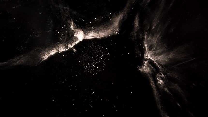 Abstract dust and light particles swirl in dark space resembling a galaxy or cosmic explosion