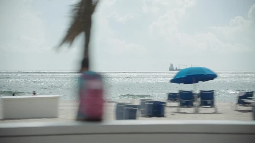 Beach with chairs and umbrellas and a ship in the background