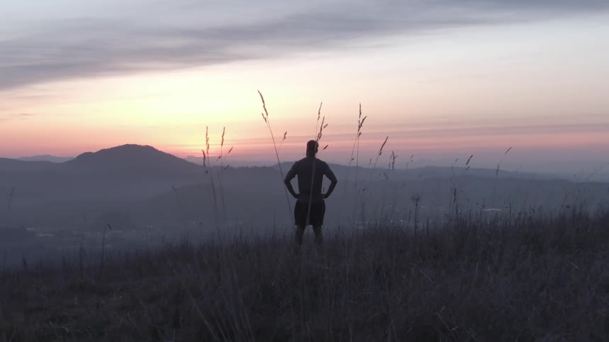 Silhouette of a man on a mountain with a sunrise sky