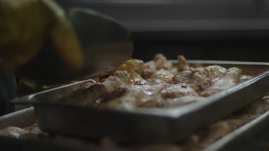 A cook is pouring sauce on the chicken in the pan