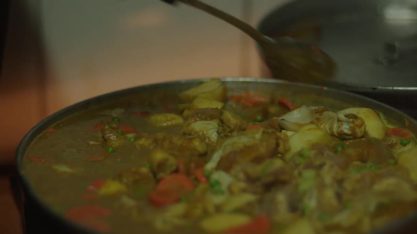 A person is mixing a big pot full of food