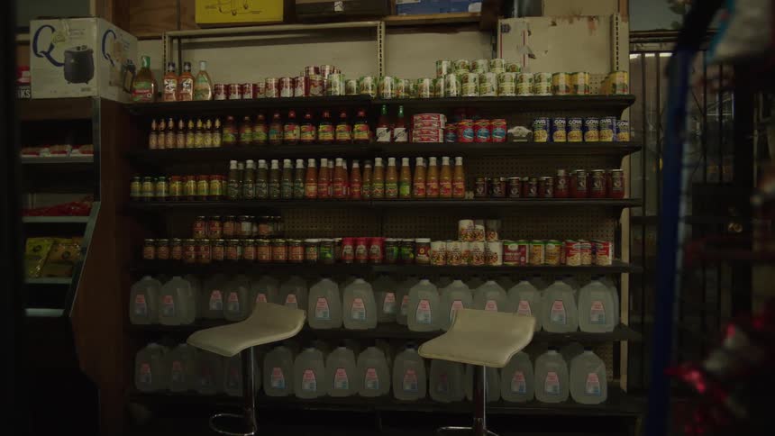 The employee is standing by the shelves full of food