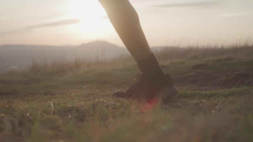 A man skipping rope on a grassy hill at sunset