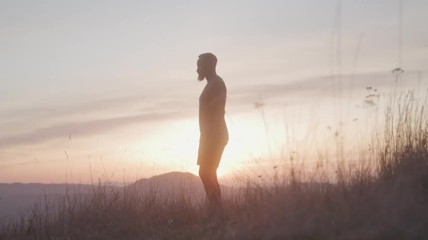 The man watching the sunset on the mountain looks up