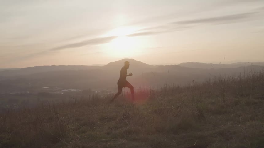 A man running up a hill at sunrise during a workout session