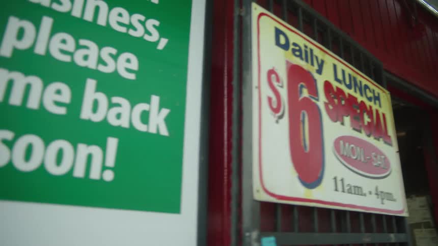 A woman walking into a restaurant with a sign out front that reads daily lunch 6 special mon to sat 11 am to 4 pm