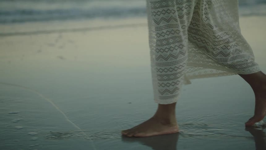 A woman is walking on the wet sand