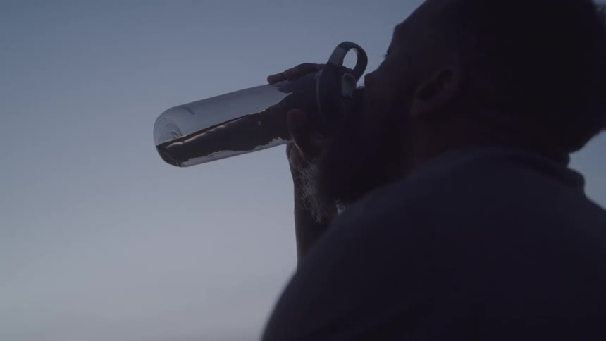 A man takes a large drink from his water bottle