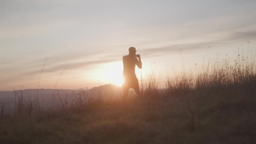 The man is shadowboxing on the mountain