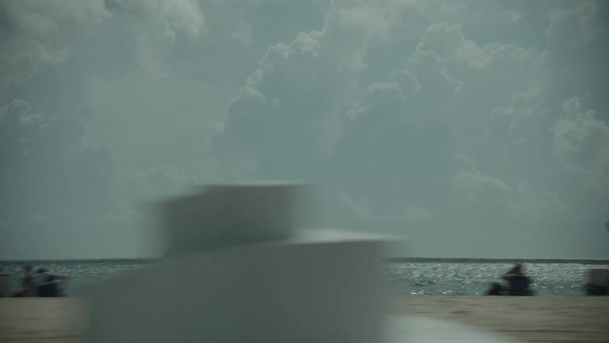 View of a beach during the day and a cargo ship on the horizon