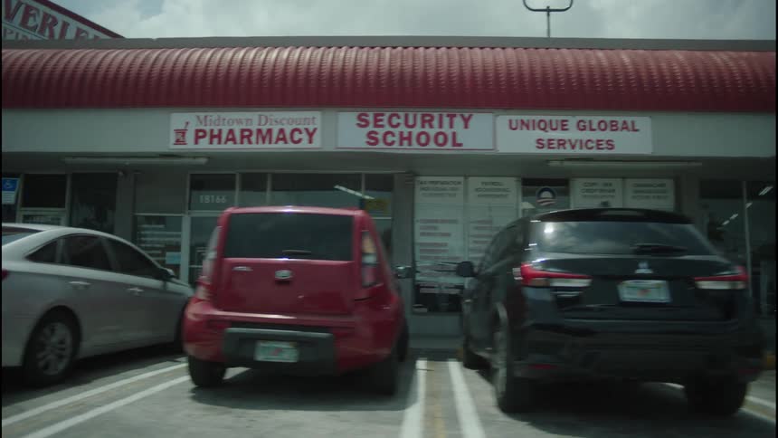 Several of the parking spaces near the shops in a strip mall are filled on a cloudy day