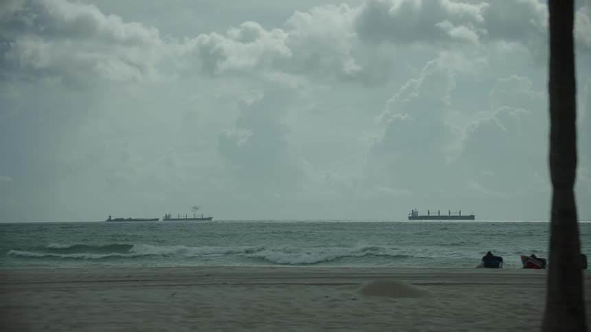 Little busy beach and cargo ships in the background
