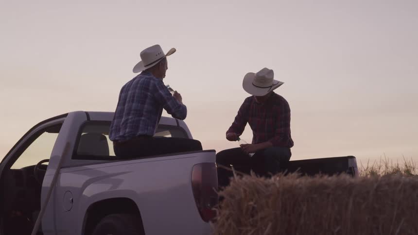 Two men drink water in the back of the pickup truck