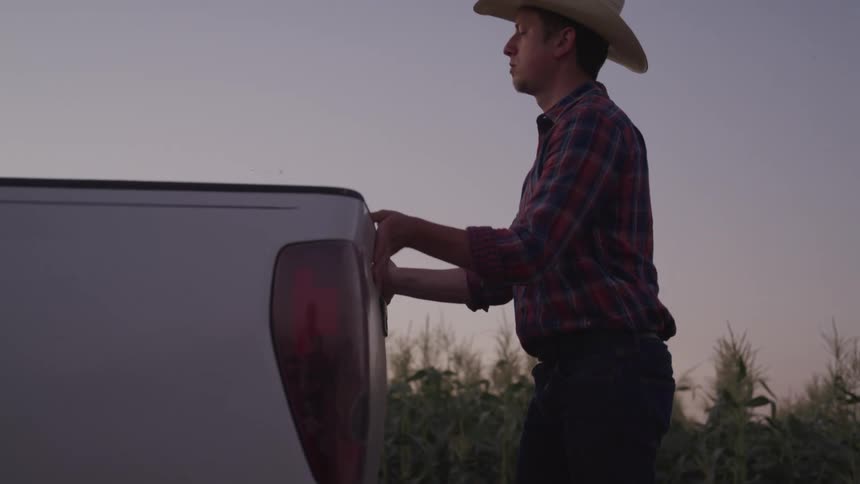 A farmer closes the back door of his pickup truck
