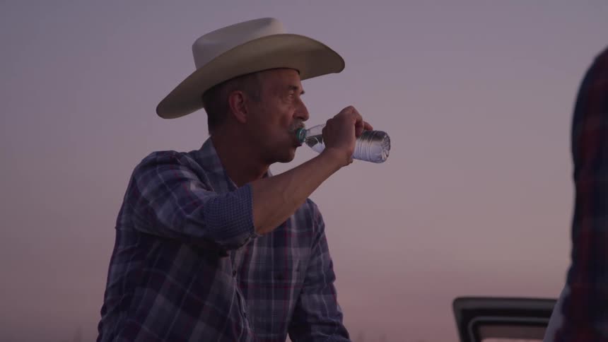 A man is sitting on the vehicle and drinking water
