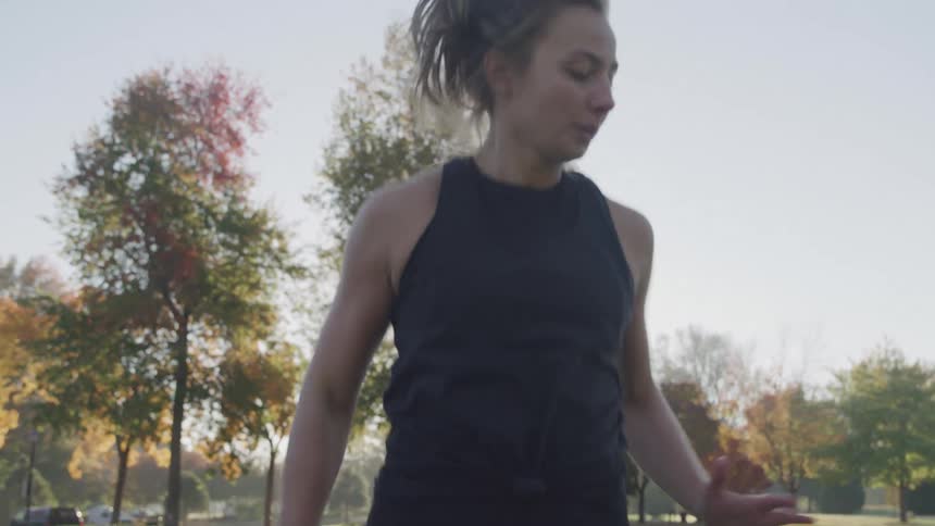 A young woman exercises by performing spotrunning outdoors during daytime