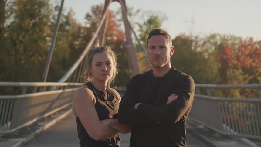 A man and woman have their arms folded on the bridge