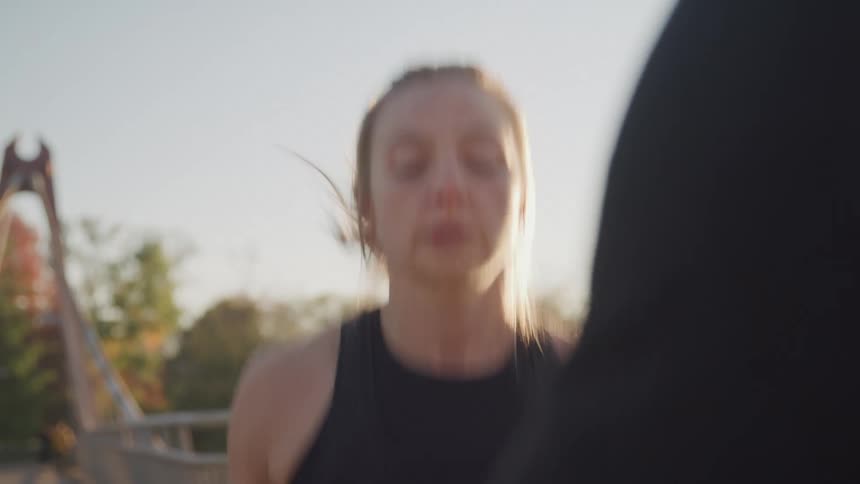 Female doing jumpin jacks outdoors while being timed by her trainer