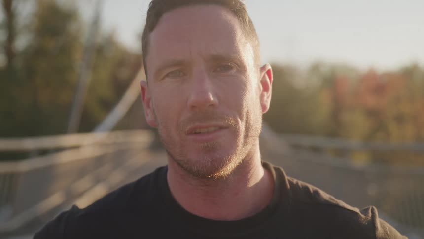 Close up portrait of a young caucasian man standing outdoors on a bridge during the day