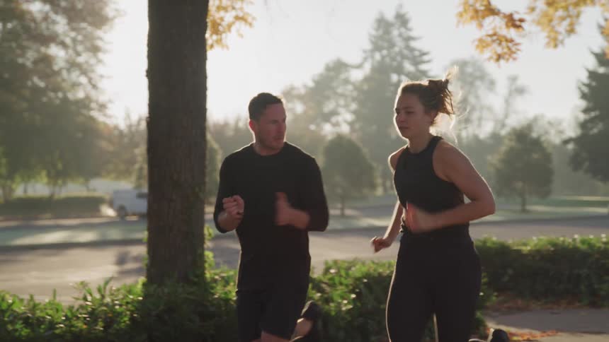 A man and woman run together on a sunny day