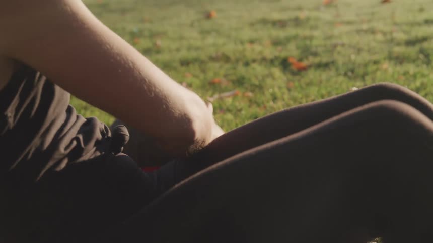 Close up of a young woman doing side to side reps while holding a fitness ball on a field during the day