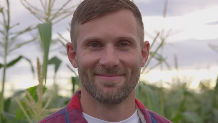 Close up portrait of a smiling caucasian man standing outdoors at a farm during the day