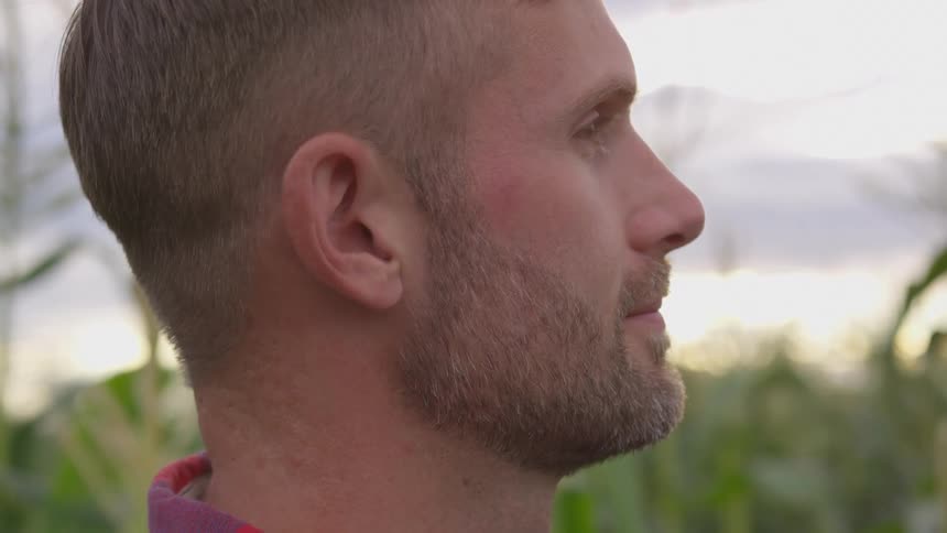 Close up of a mans face outdoors as he stares contemplatively