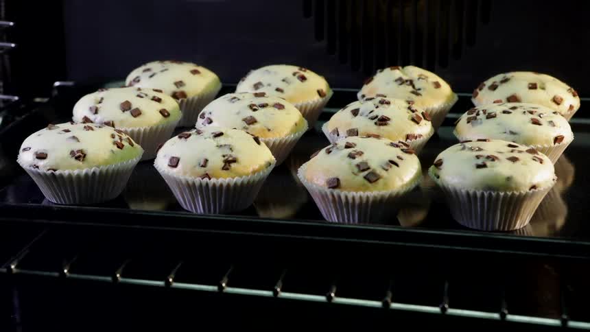 Cupcake liners in the oven rise into golden chocolate chip muffins
