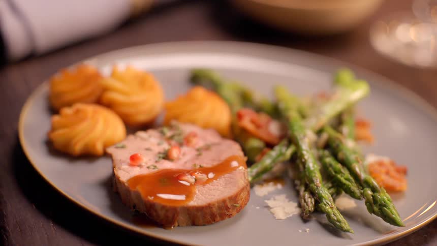 A spoon serving sauce over pork meat on a plate of food