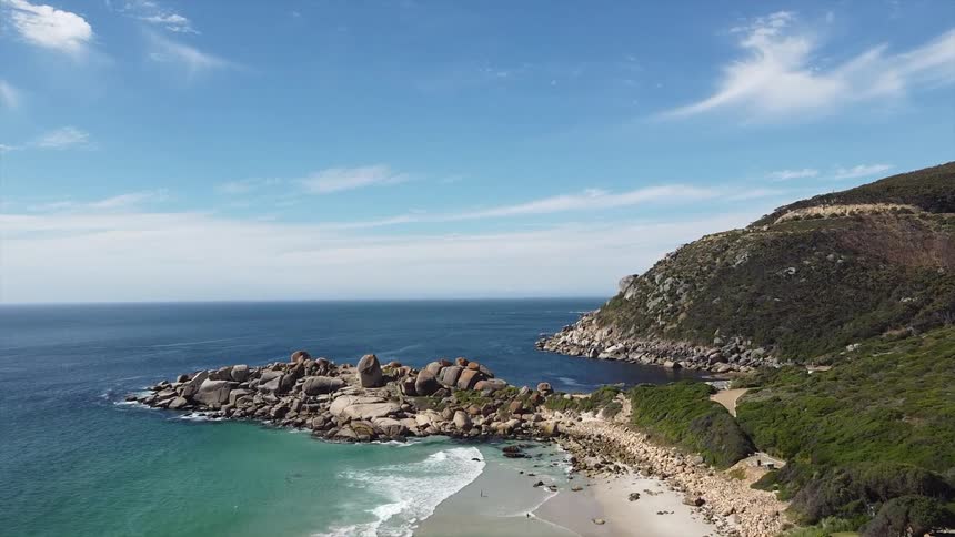 An island with ocean waves gently lapping against its coastline at midday